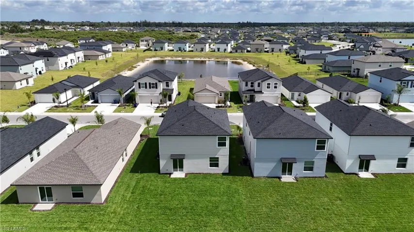 Expansive residential development featuring modern homes, manicured green spaces, and a central water feature