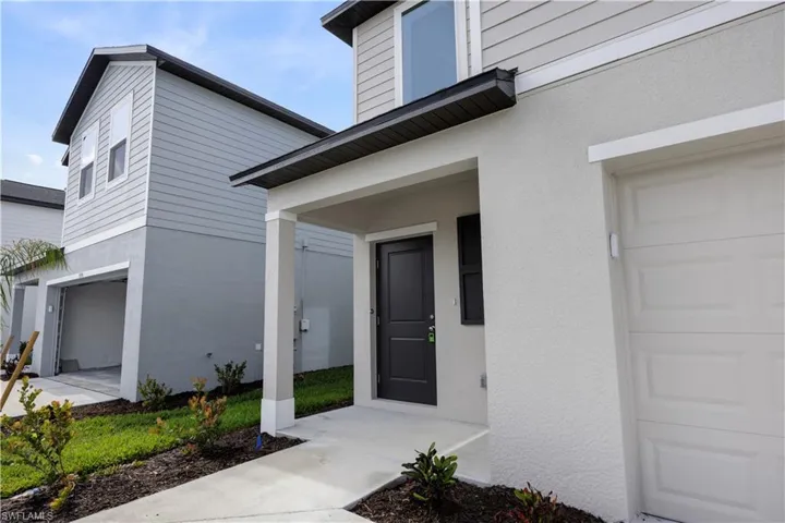 Contemporary exterior featuring a textured stucco finish, dark entry door with sidelight, and a covered porch