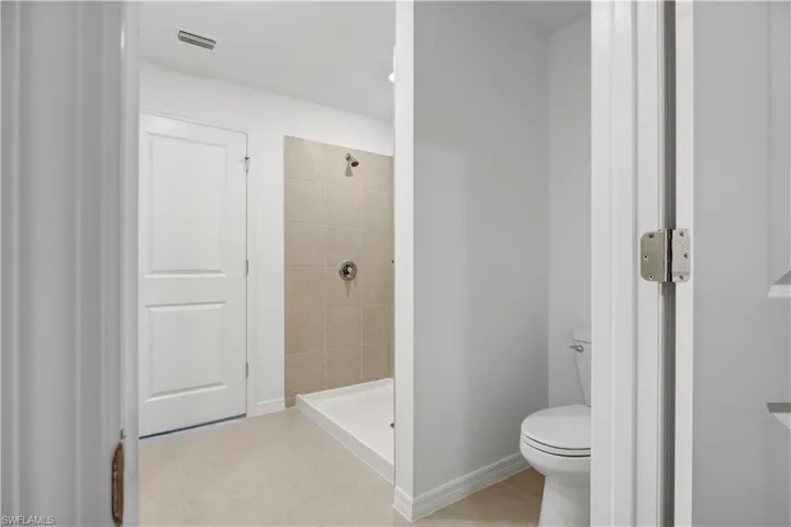 Enclosed shower with neutral-toned wall tiling and a white base