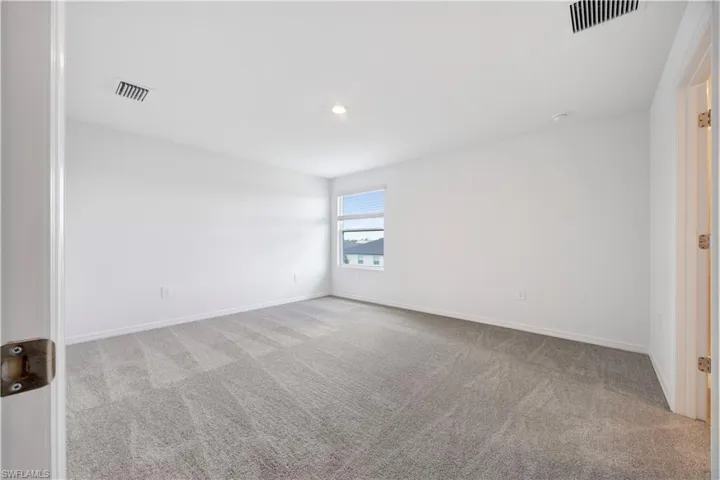Expansive room featuring light gray patterned carpeting and white walls