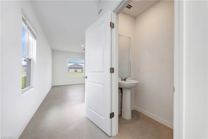 Powder room featuring a pedestal sink with a chrome faucet and a wall-mounted mirror