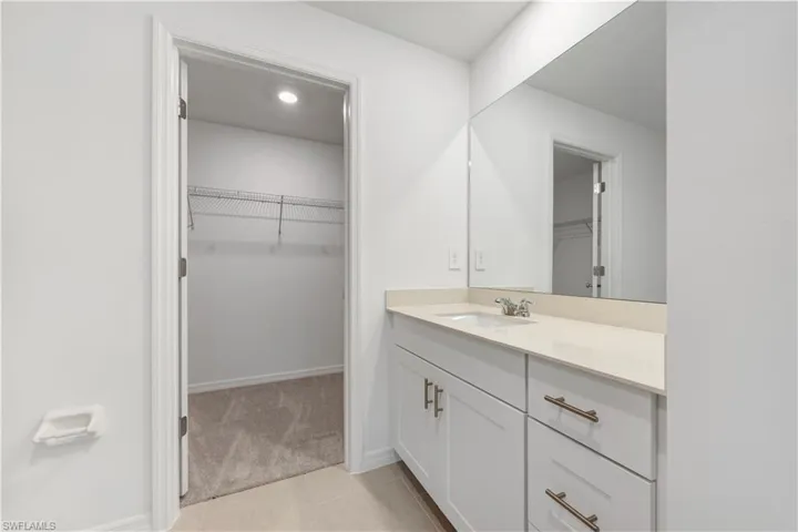 Vanity featuring a white undermount sink, a chrome faucet, and a light-toned countertop