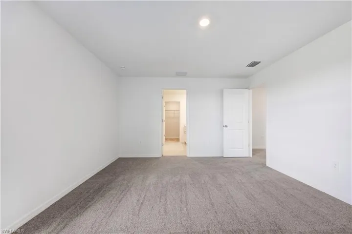 Spacious room featuring neutral carpeting, white painted walls, and a recessed ceiling light