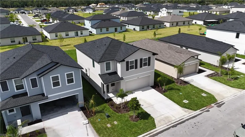 Contemporary residential property featuring a gray facade, dark shingles, an integrated garage, and a concrete driveway