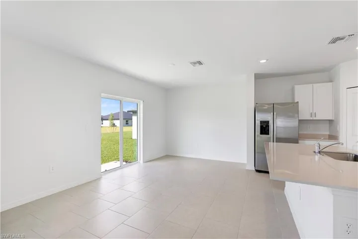 Open-concept living space featuring light-toned tile flooring, white walls, and recessed lighting