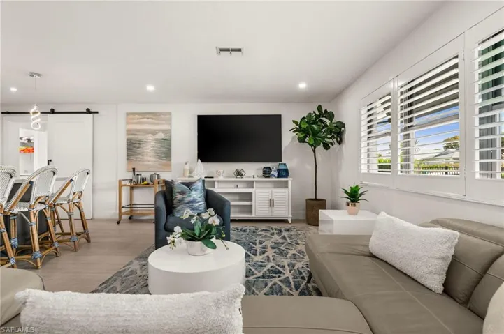 Living area with a barn door, wood finished floors, and recessed lighting