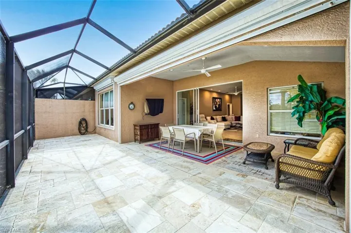 View of patio featuring a sunroom, a ceiling fan, glass enclosure, and outdoor dining area