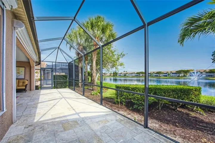 Unfurnished sunroom with a water view, lofted ceiling, and a patio