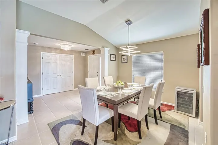 Dining space with vaulted ceiling, light tile patterned floors, and a chandelier