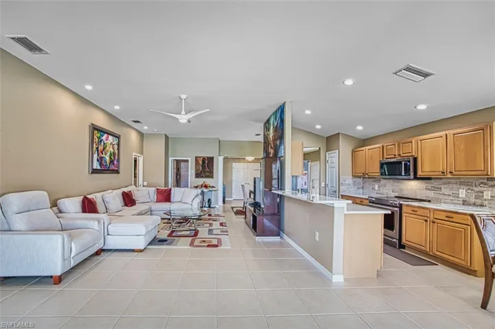 Living room with vaulted ceiling, recessed lighting, light tile patterned floors, and a ceiling fan