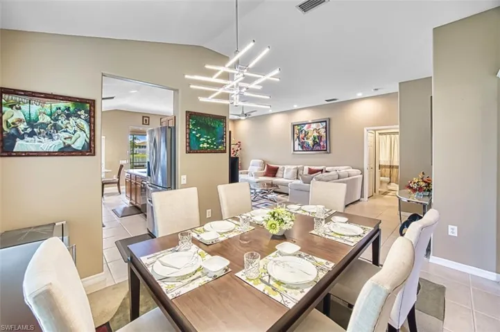 Dining space with light tile patterned floors, lofted ceiling, a chandelier, and recessed lighting