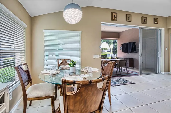 Dining area with light tile patterned flooring, a chandelier, and vaulted ceiling
