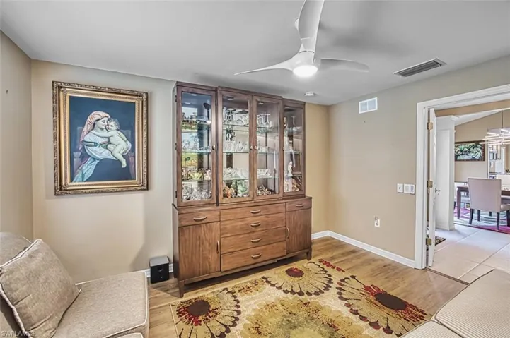 Living area featuring ceiling fan, light wood-style floors, and decorative columns