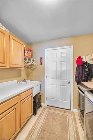 Laundry area featuring light tile patterned floors, independent washer and dryer, and cabinet space