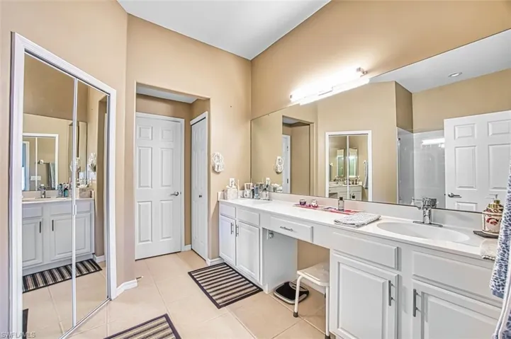 Full bath with double vanity, light tile patterned floors, and a walk in shower