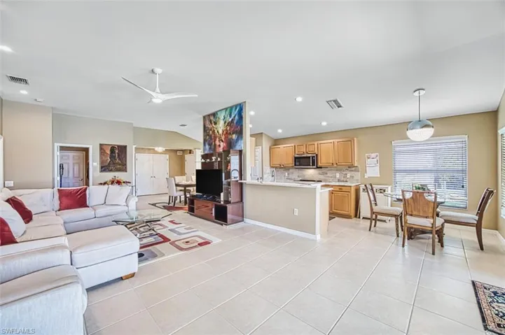 Living room with recessed lighting, vaulted ceiling, light tile patterned flooring, and a ceiling fan