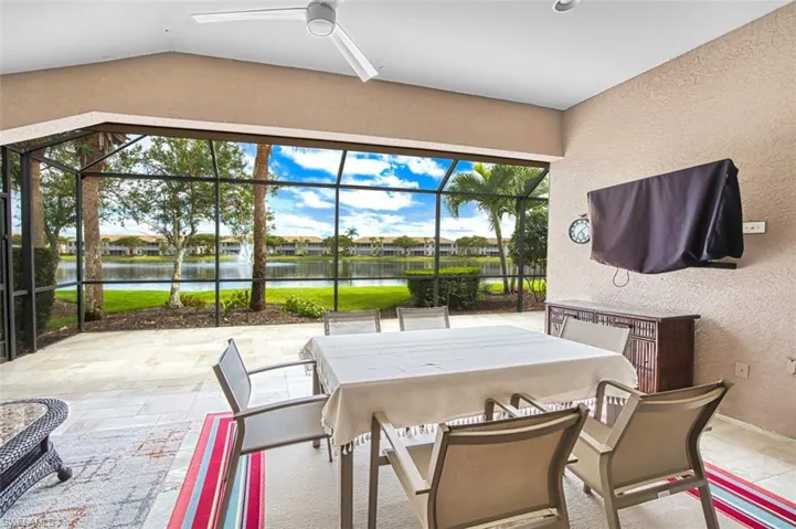 View of patio featuring a sunroom, a water view, a lanai, and outdoor dining space