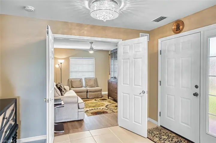 Foyer entrance with light tile patterned floors, a chandelier, and ceiling fan
