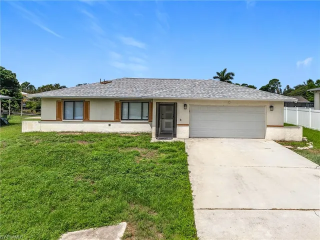 Ranch-style home with stucco siding, an attached garage, and driveway