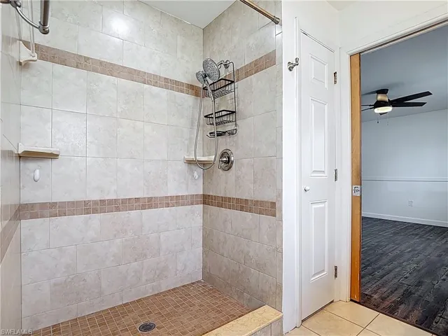 Full bathroom with tiled shower, tile patterned flooring, and ceiling fan