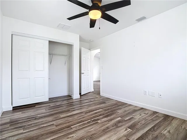 Unfurnished bedroom with dark wood finished floors, a closet, and ceiling fan