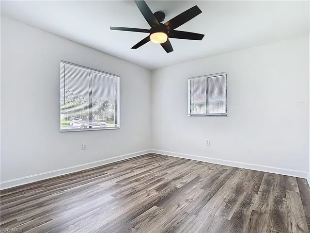 Empty room featuring healthy amount of natural light, wood finished floors, and a ceiling fan