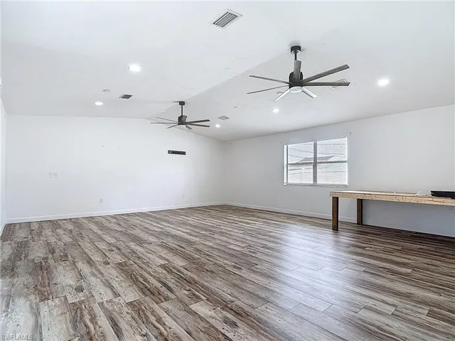 Spare room with wood finished floors, ceiling fan, vaulted ceiling, and recessed lighting