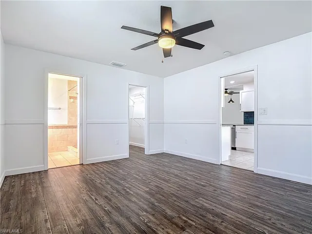 Unfurnished bedroom featuring wood finished floors, ensuite bathroom, a walk in closet, and a closet