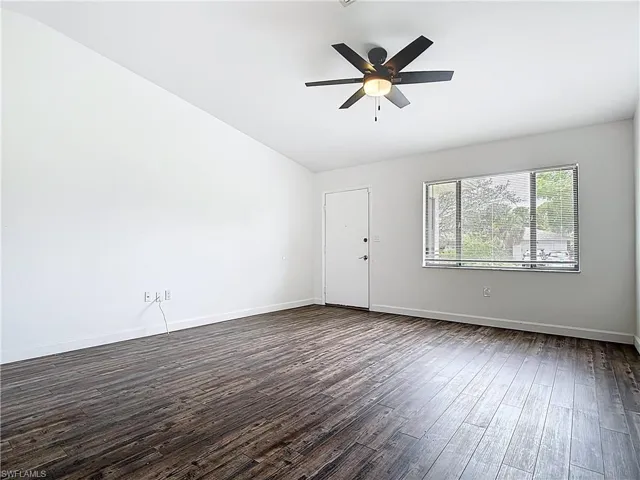 Unfurnished room with vaulted ceiling, dark wood-type flooring, and ceiling fan