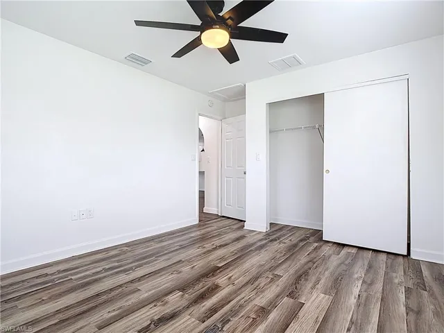 Unfurnished bedroom with wood finished floors, a closet, and a ceiling fan