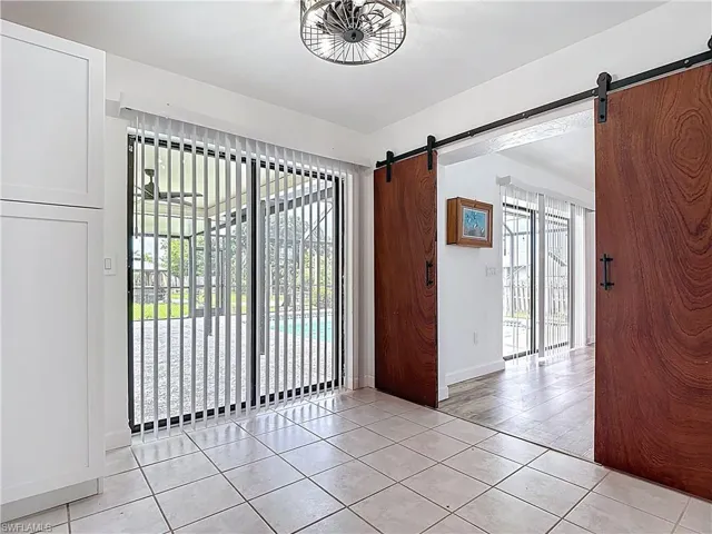 Empty room with a barn door and light tile patterned flooring