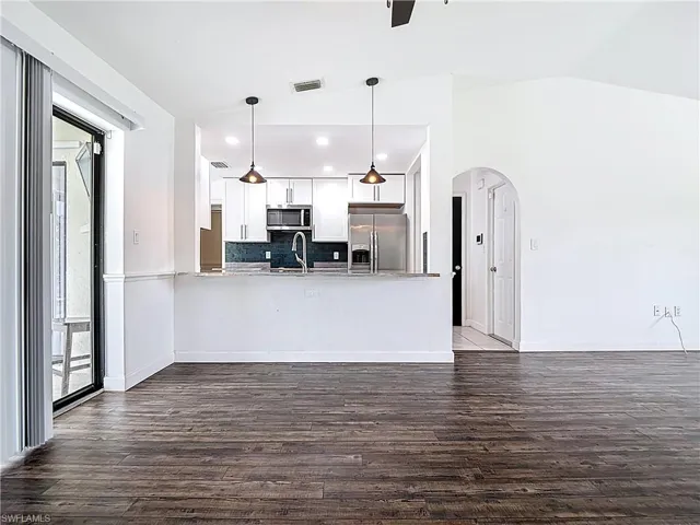 Kitchen with appliances with stainless steel finishes, vaulted ceiling, arched walkways, a peninsula, and light countertops