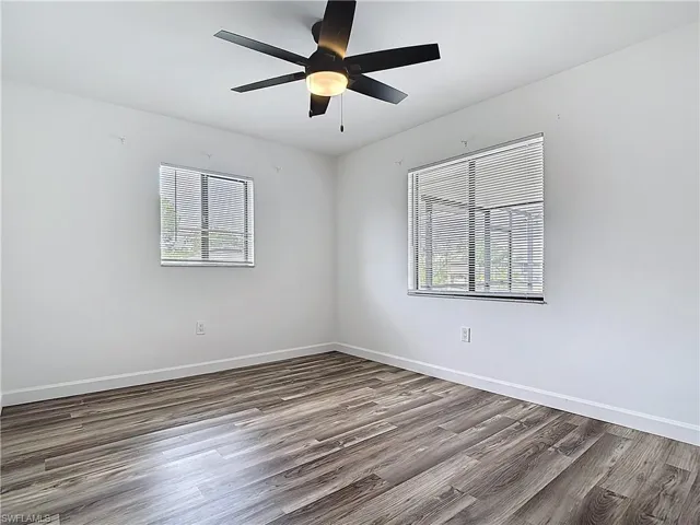 Unfurnished room with healthy amount of natural light, wood finished floors, and a ceiling fan