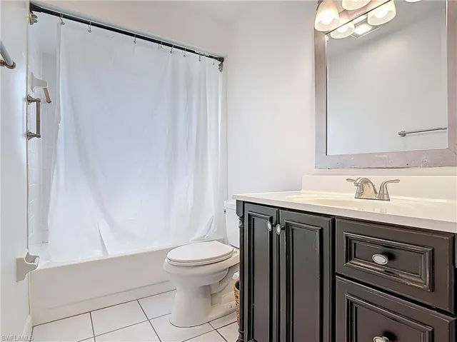 Full bathroom with tile patterned flooring, vanity, and shower / bath combo with shower curtain