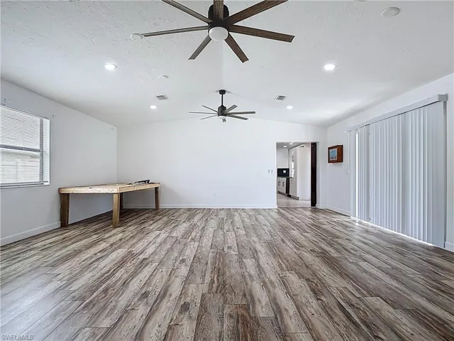 Unfurnished living room featuring ceiling fan, wood finished floors, lofted ceiling, and recessed lighting