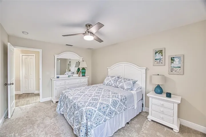 Bedroom featuring light carpet, baseboards, and a ceiling fan
