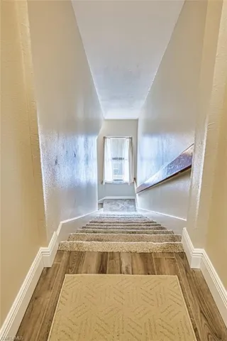 Staircase with wood finished floors and baseboards