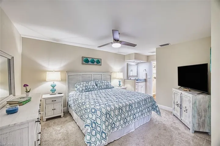 Bedroom featuring light carpet, baseboards, and a ceiling fan