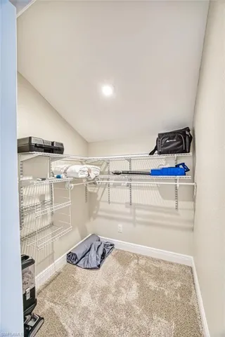 Walk in closet with carpet floors and lofted ceiling