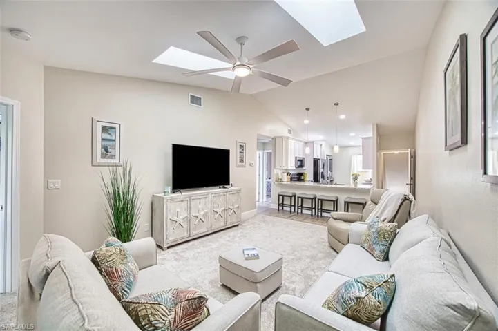Living area with a skylight, vaulted ceiling, a ceiling fan, and baseboards