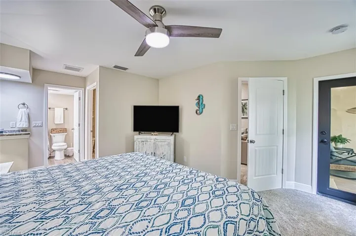 Bedroom featuring carpet floors, connected bathroom, a ceiling fan, and baseboards