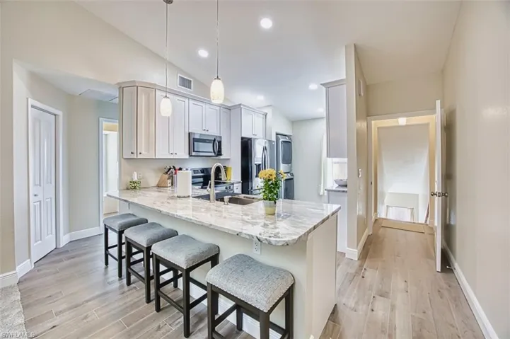 Kitchen featuring stainless steel appliances, a sink, a kitchen bar, light wood-style floors, and a peninsula