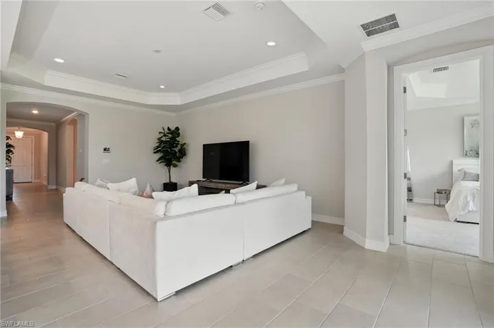 Living room with a tray ceiling, crown molding, and tile patterned flooring