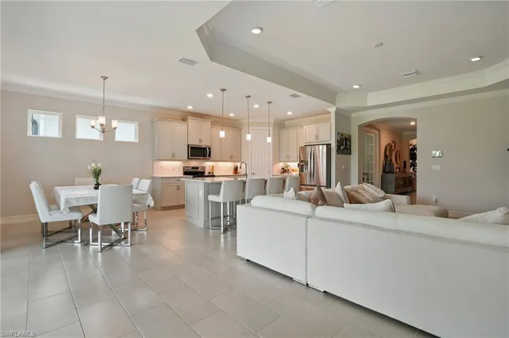 Kitchen with appliances with stainless steel finishes, light tile patterned floors, an island with sink, open floor plan, and hanging light fixtures