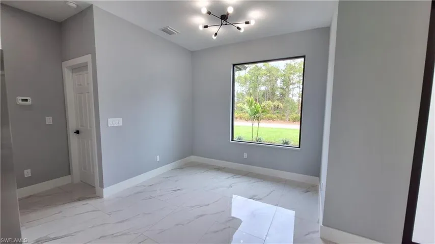 Unfurnished room featuring light marble finish flooring and suspended lighting