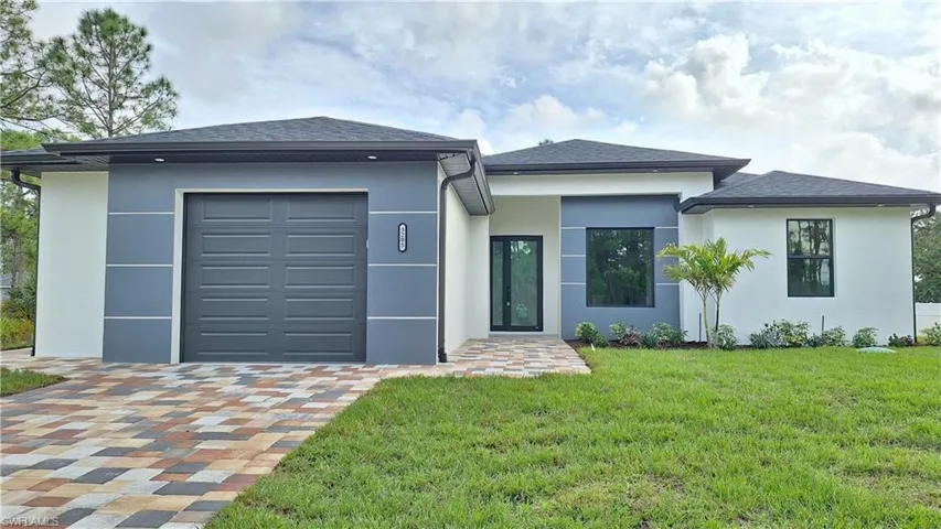 View of front of house with a garage, stucco siding, and a front lawn