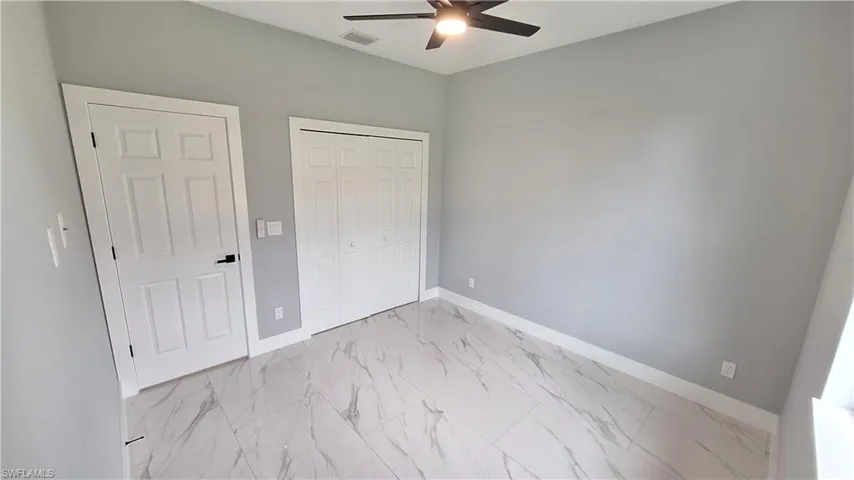 Unfurnished bedroom featuring a closet, light marble finish flooring, and a ceiling fan