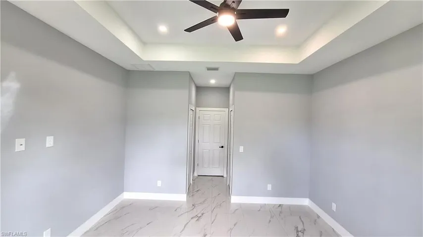 Unfurnished room with recessed lighting, ceiling fan, light marble finish flooring, and a raised ceiling