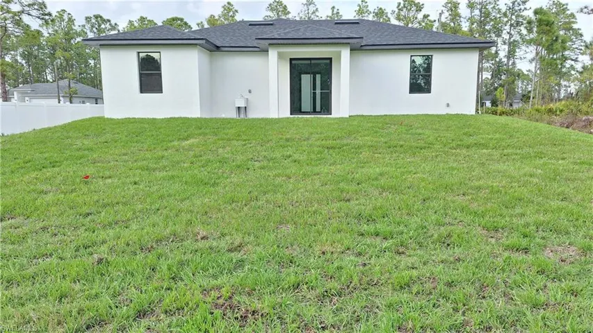 Back of house with stucco siding and roof with shingles