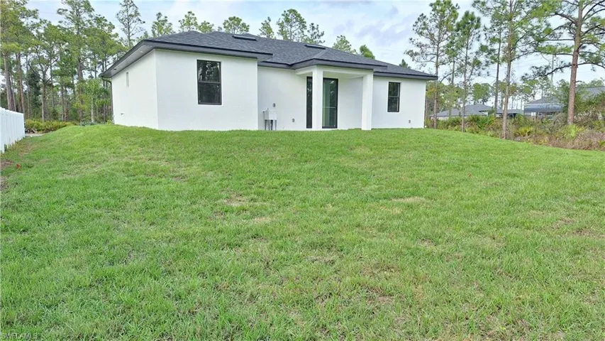 Rear view of house with stucco siding and roof with shingles